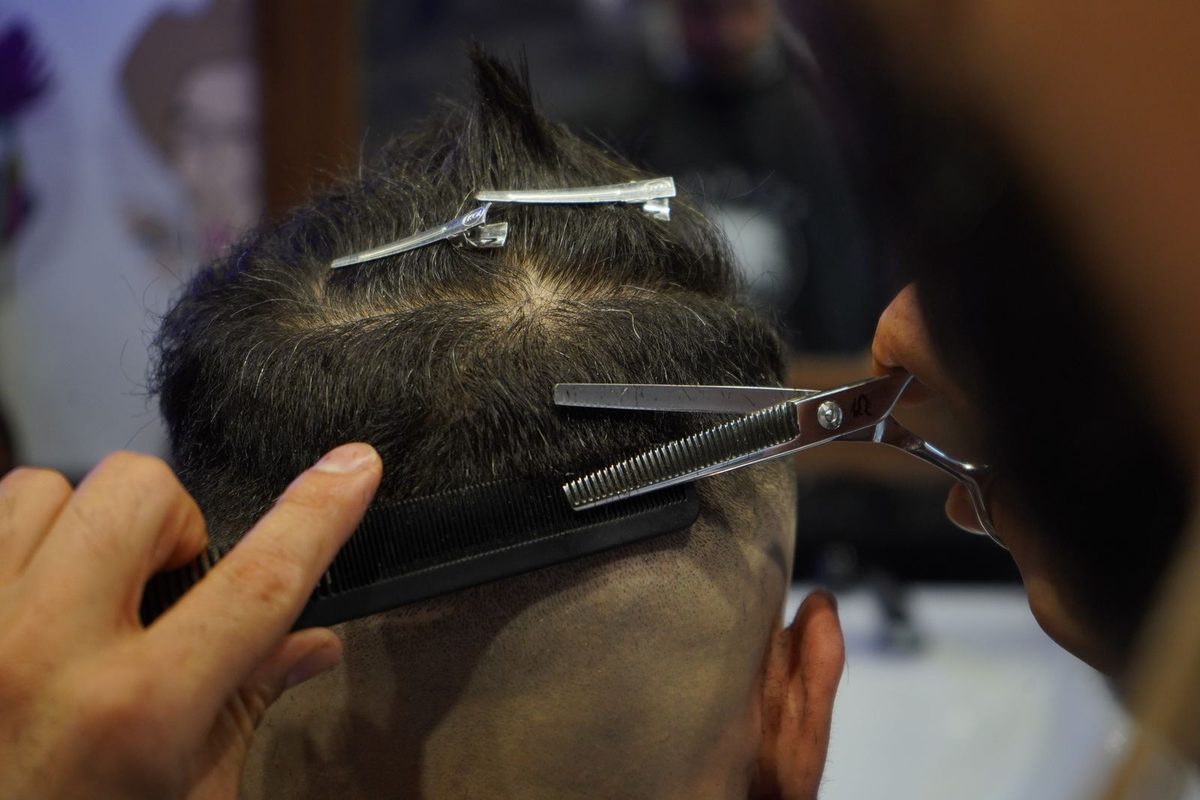 Illustrative photo: barber cutting a client’s hair with scissors